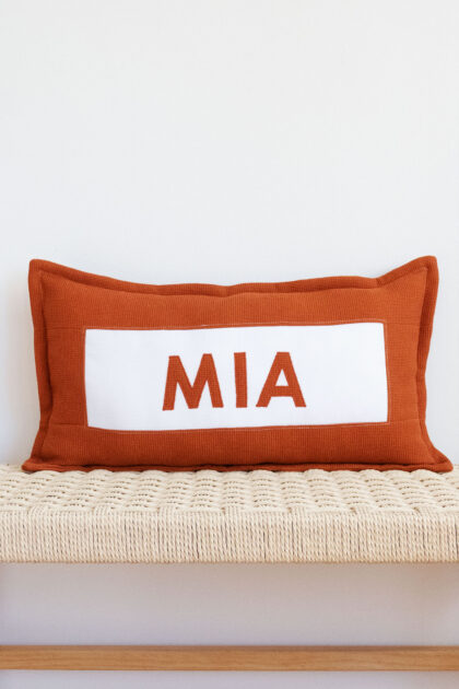 Cojín personalizado con nombre en color teja.
